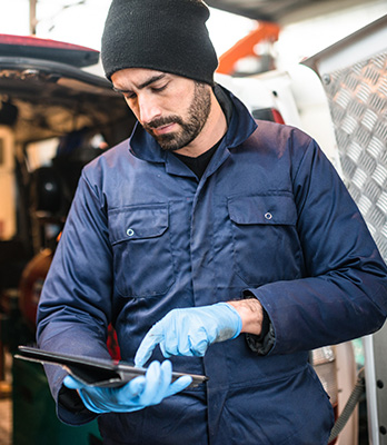 Man in coveralls looking at tablet